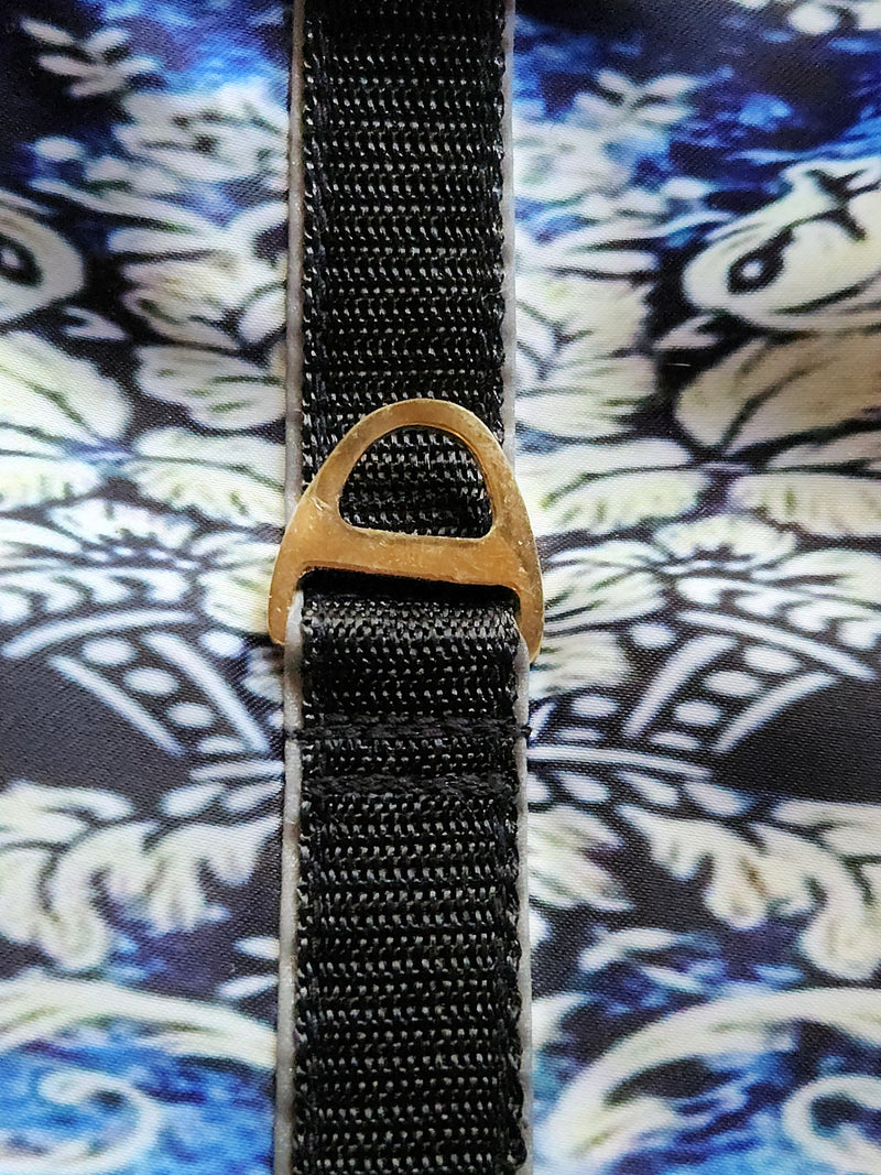 Black strap with a gold buckle on a patterned fabric background